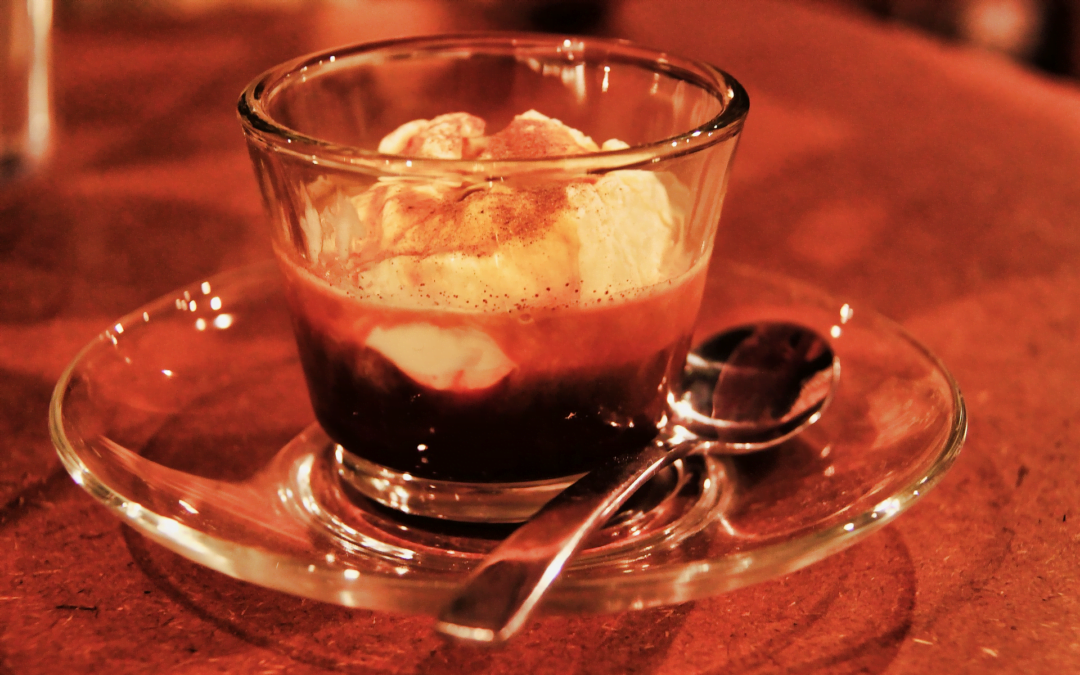 A glass of affogato with a spoon served at a restaurant after a meal.